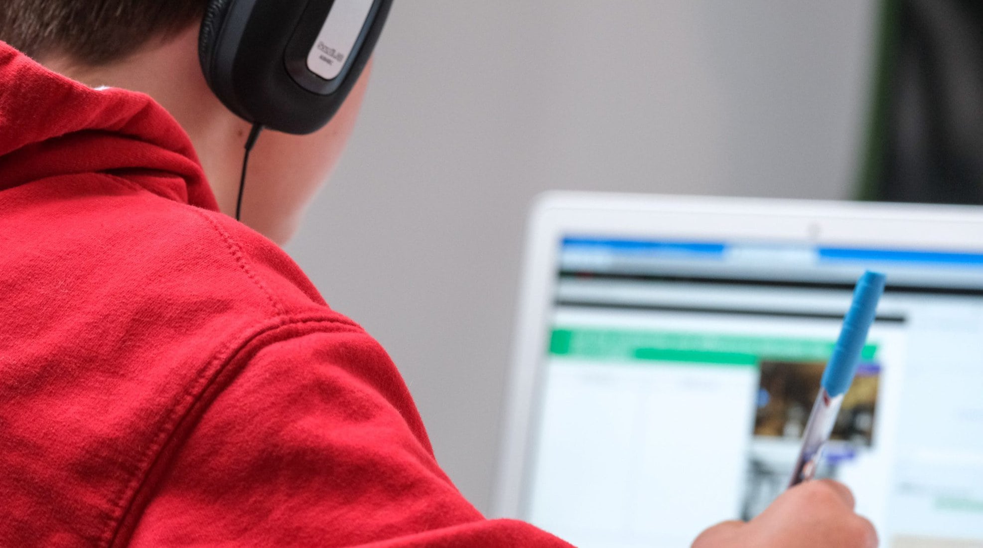 Home schooling during lockdown, boy working on school work with laptop and headphones during coronavirus covid 19 lock down. Remote learning through home schooling due to school closures has become commonplace in the UK in 2021.